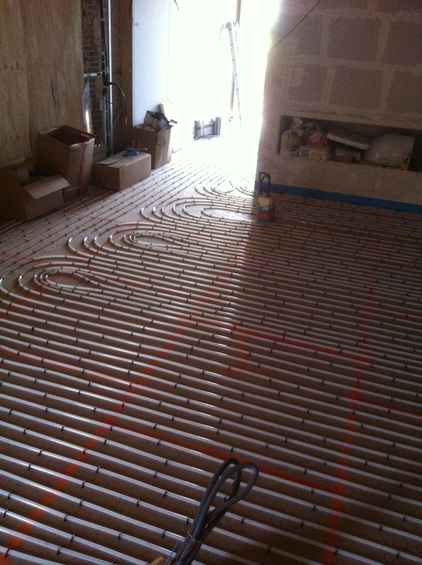 Installation d'un système de chauffage au sol à l'intérieur d'une pièce en construction.