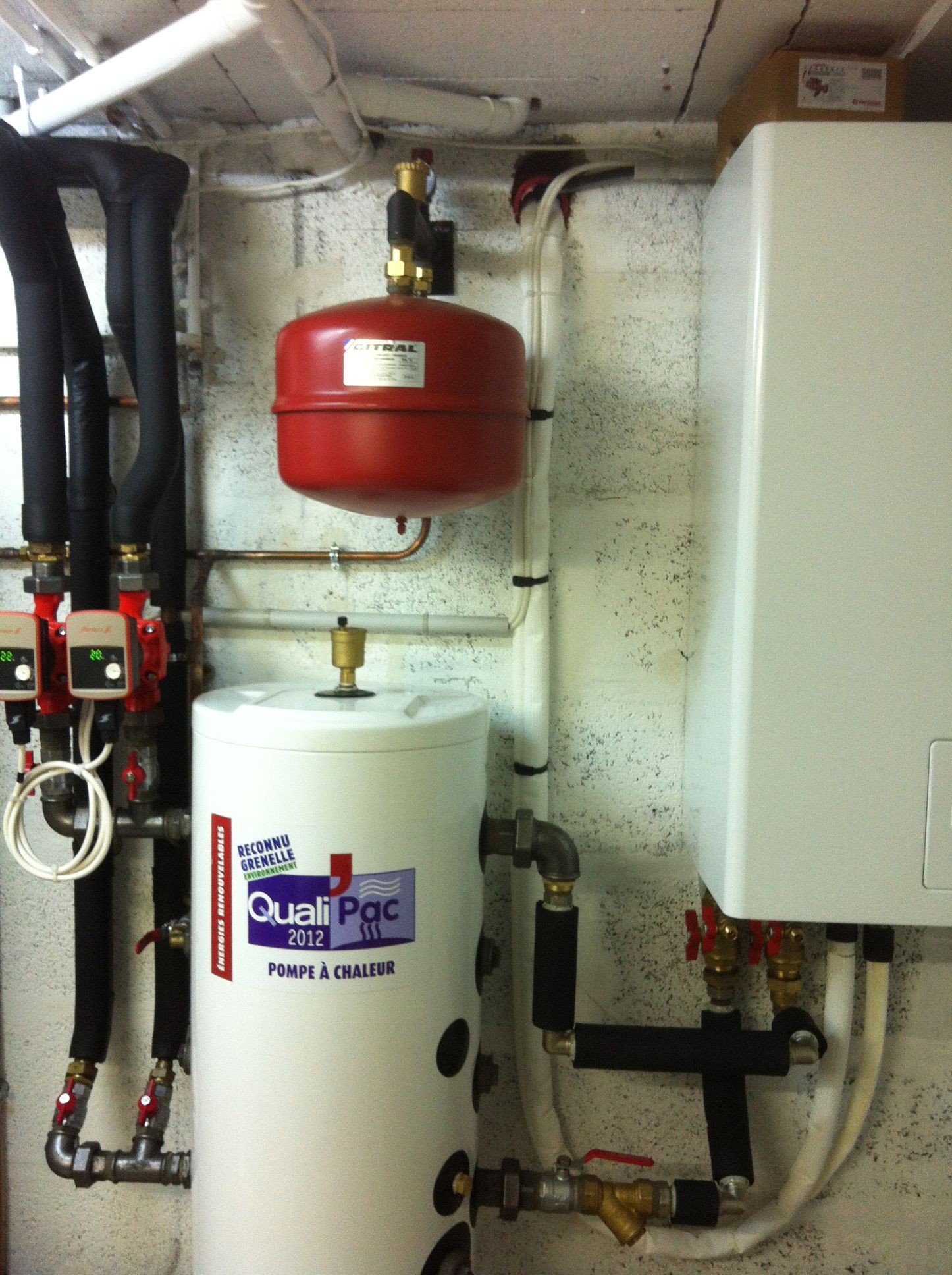 Système de chauffage avec réservoir blanc, vase d'expansion rouge et unité murale blanche.