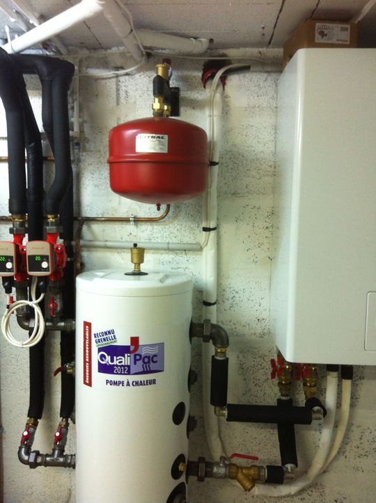 Système de chauffage avec réservoir blanc, vase d'expansion rouge et unité murale blanche.