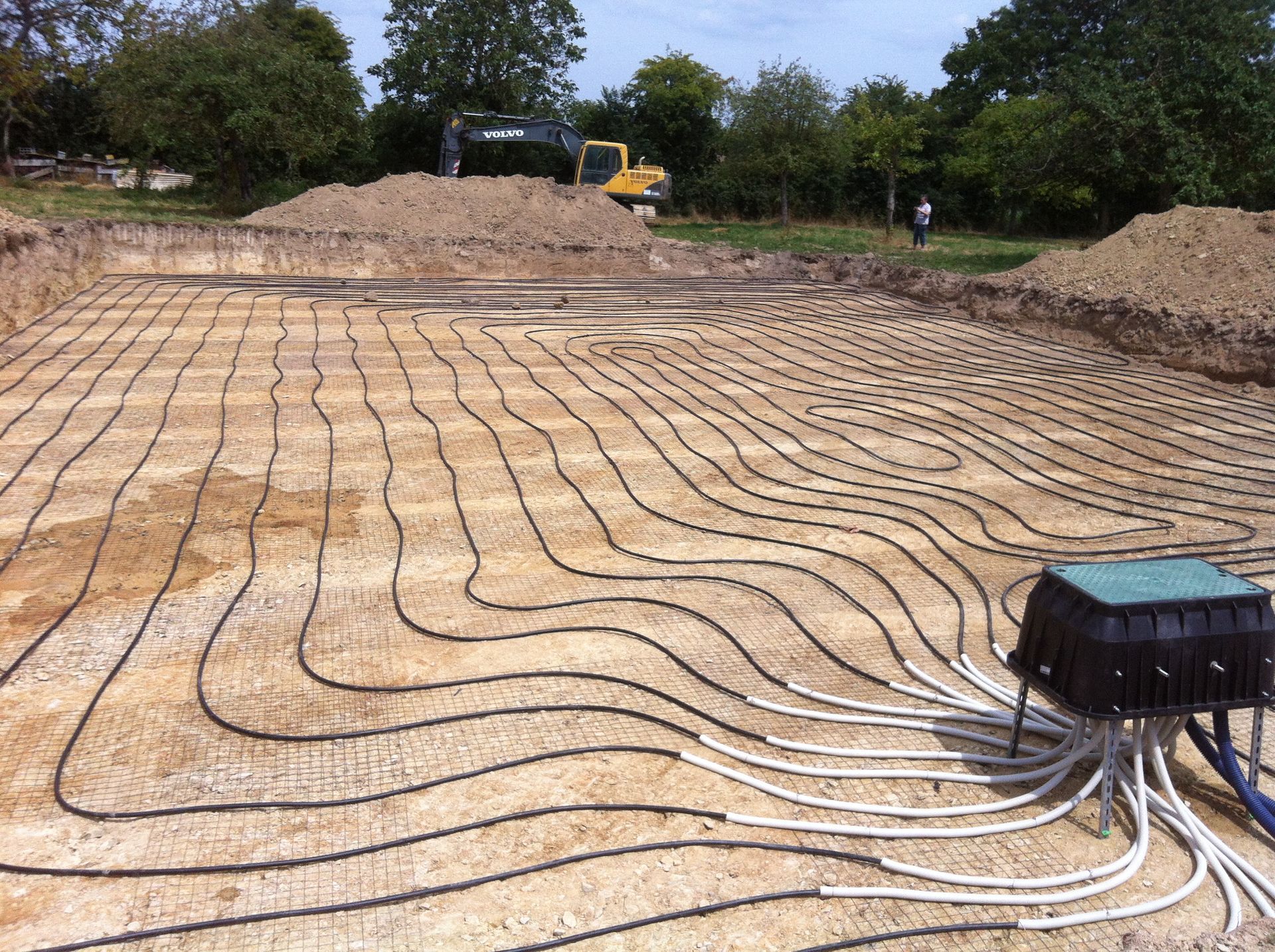 Travaux de fondation avec pose de tuyaux noirs en quadrillage.