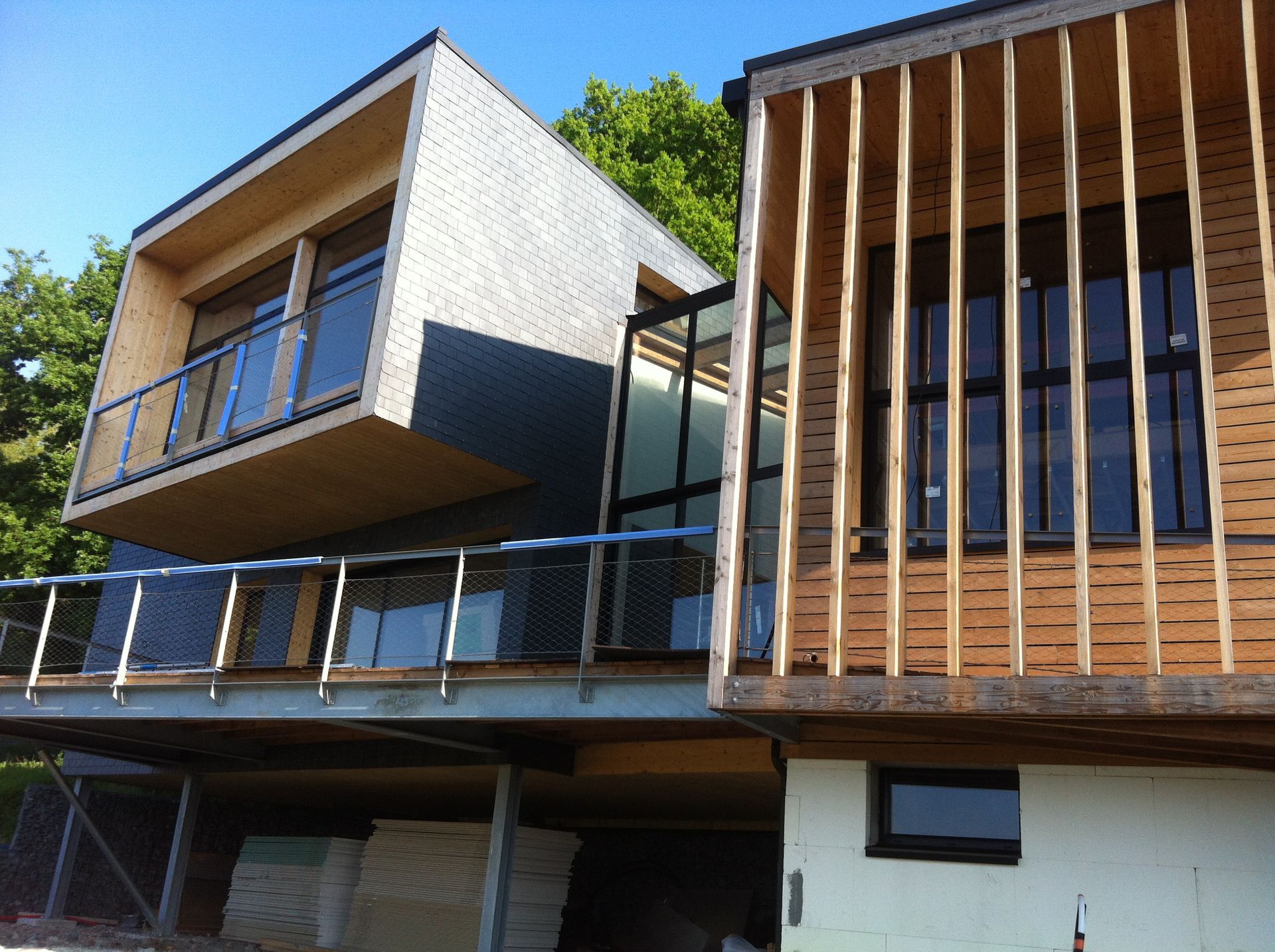 Bâtiment moderne en bois aux formes géométriques, garde-corps et lattes de bois verticales.