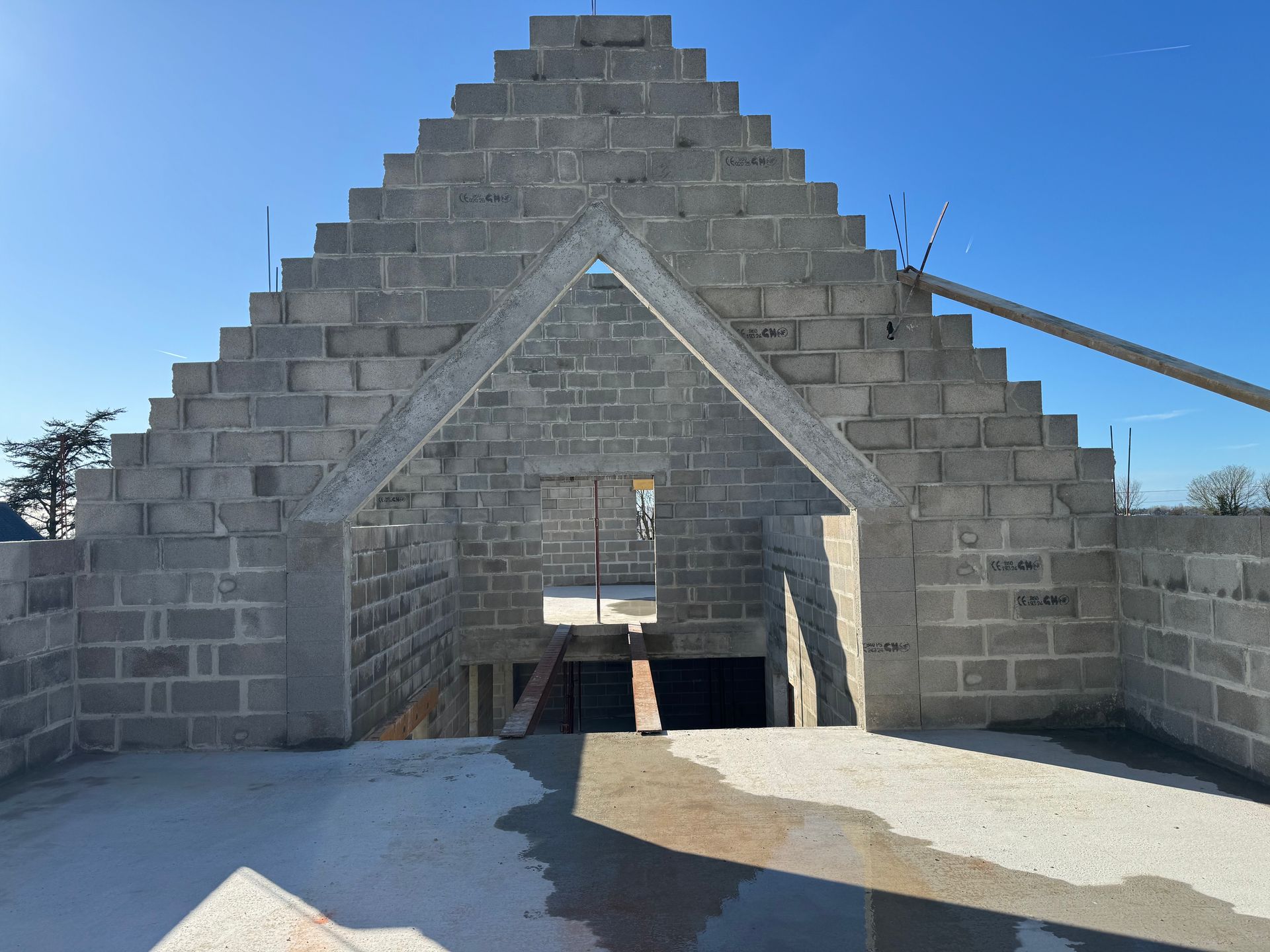 Structure en pierre en forme de pyramide, avec une porte triangulaire et un intérieur ouvert, sous un ciel bleu limpide.