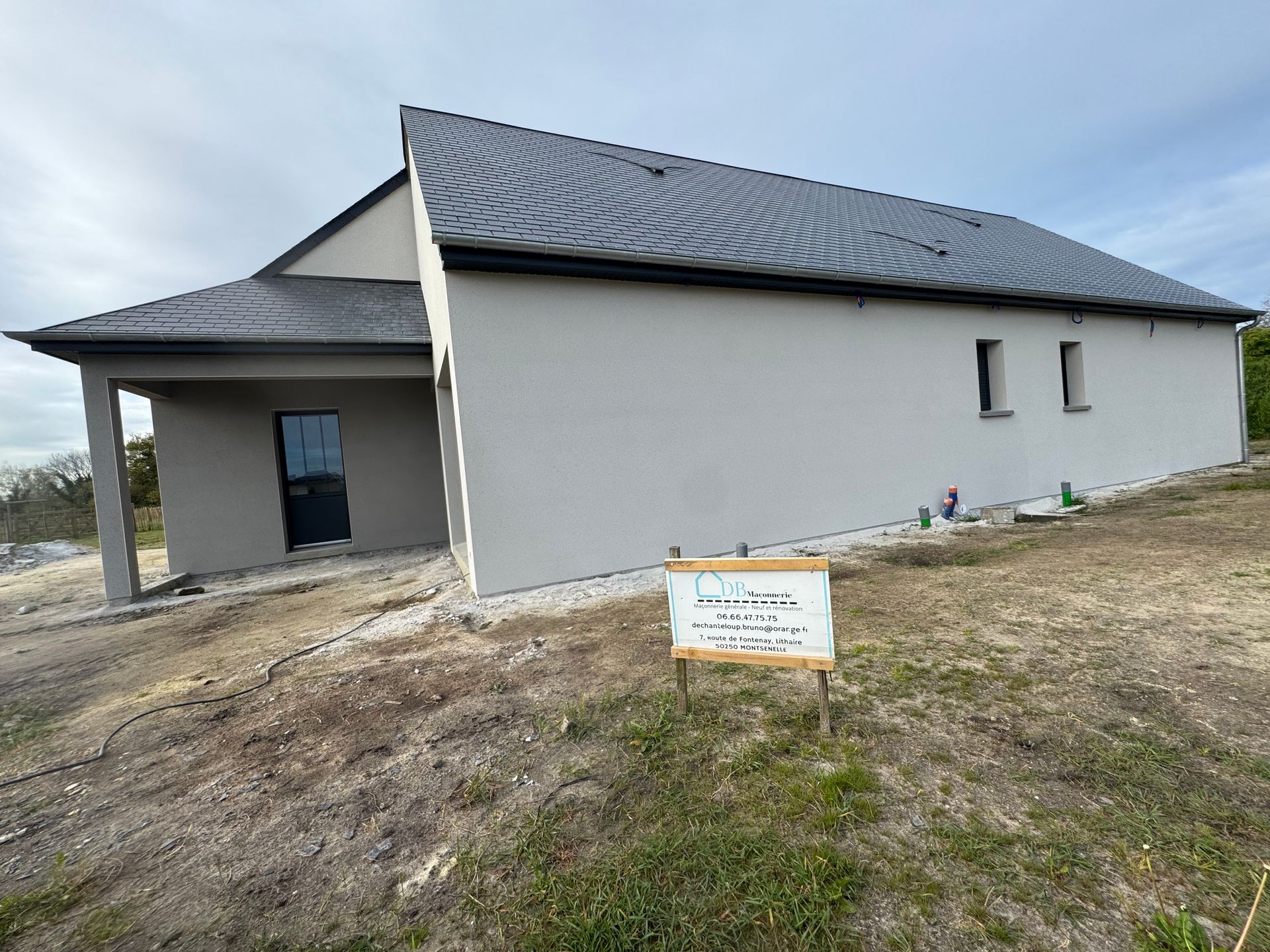 Nouvelle maison blanche à toit noir en construction sur un terrain vague