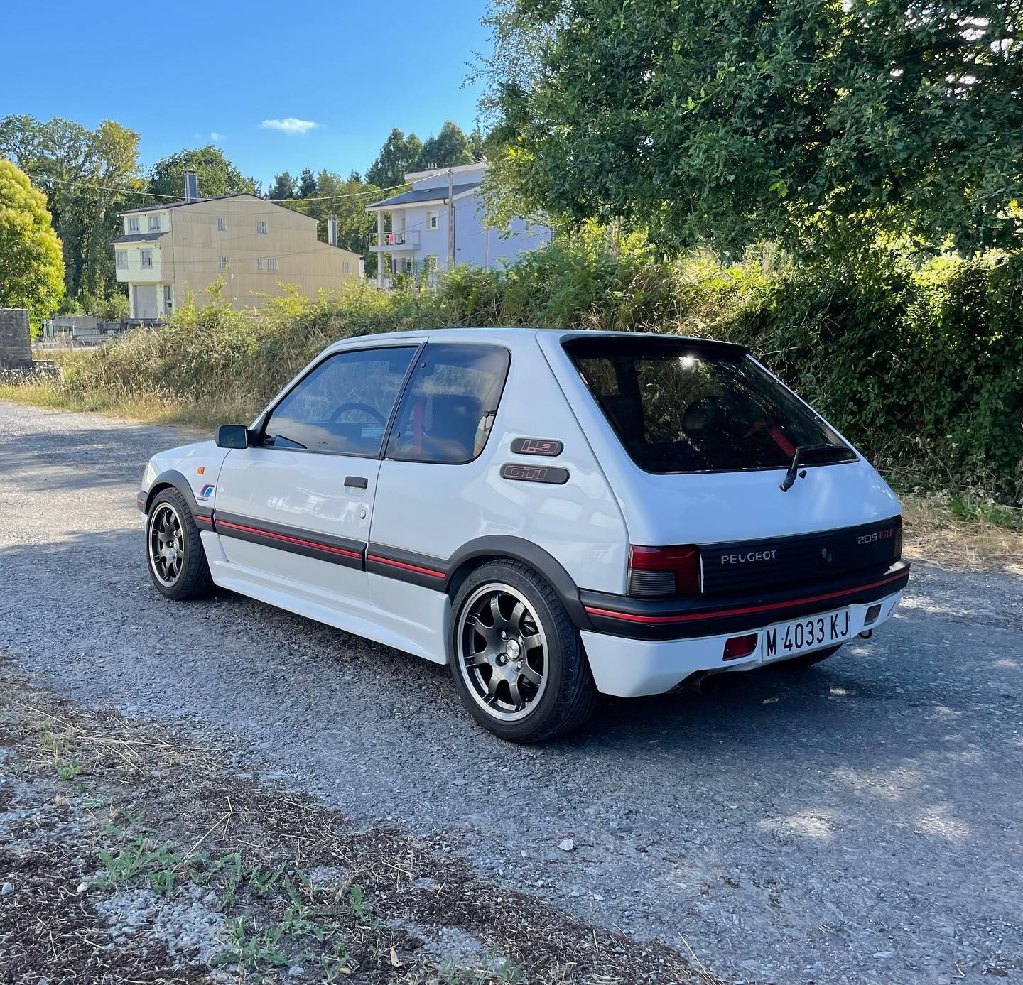 Un coche blanco está aparcado al costado de un camino de grava.