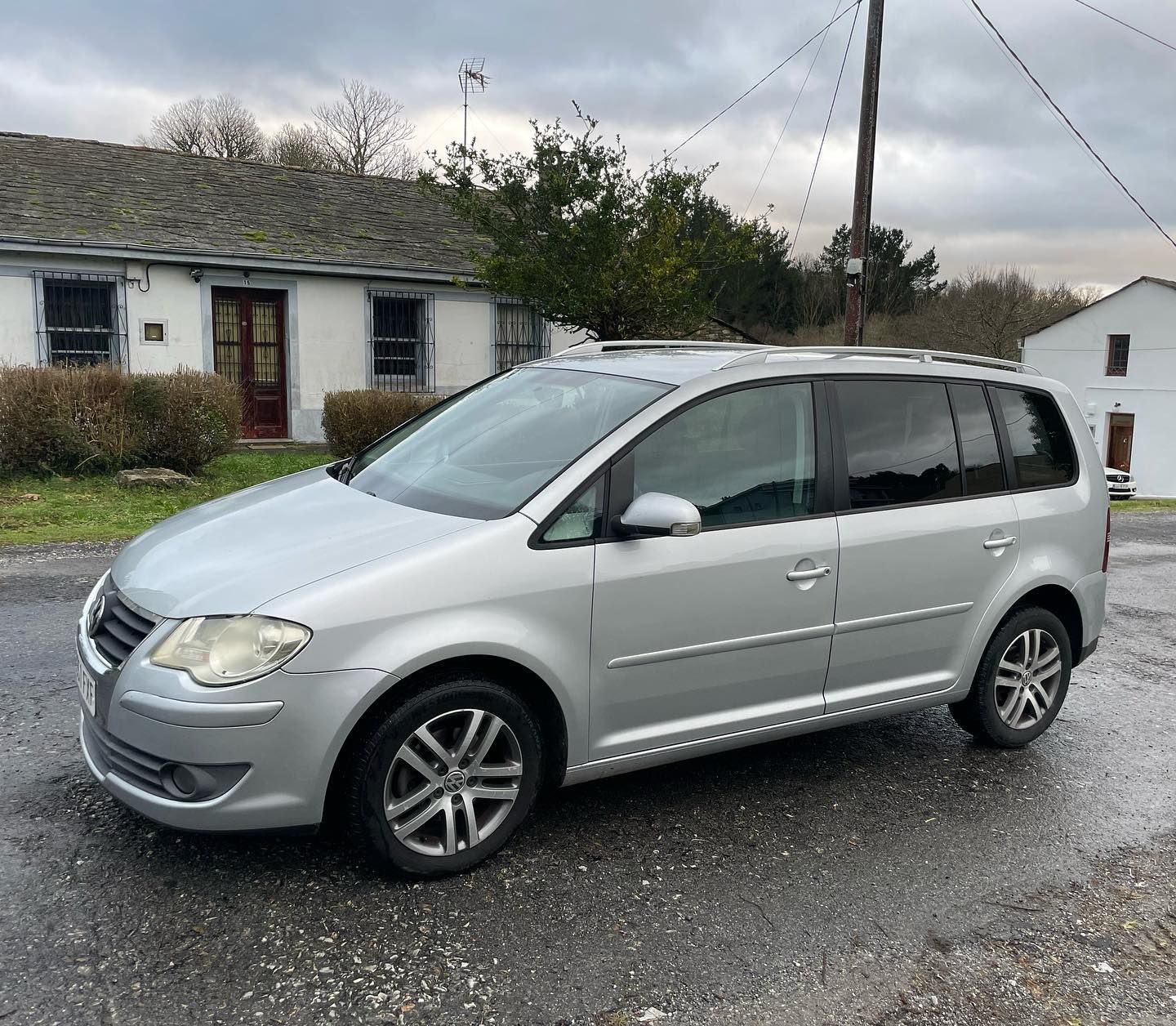 Una minivan plateada está estacionada frente a una casa.