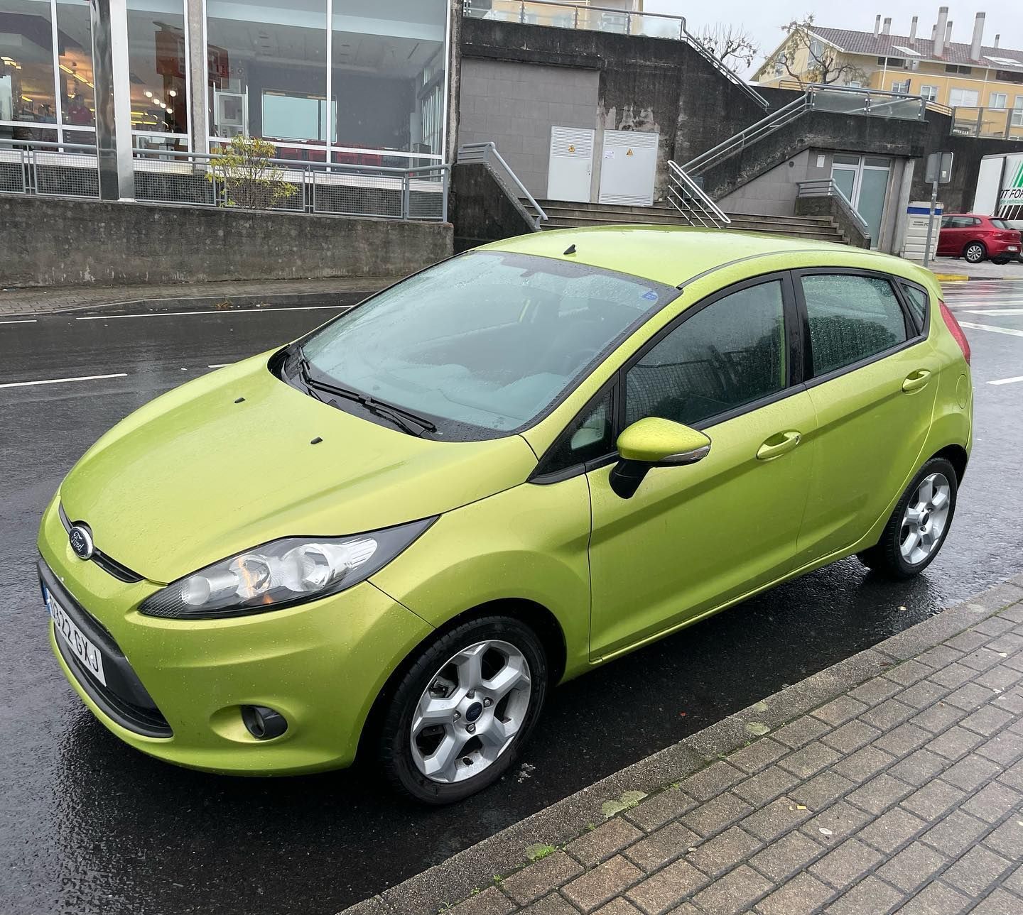 Un coche verde está aparcado al costado de la carretera.