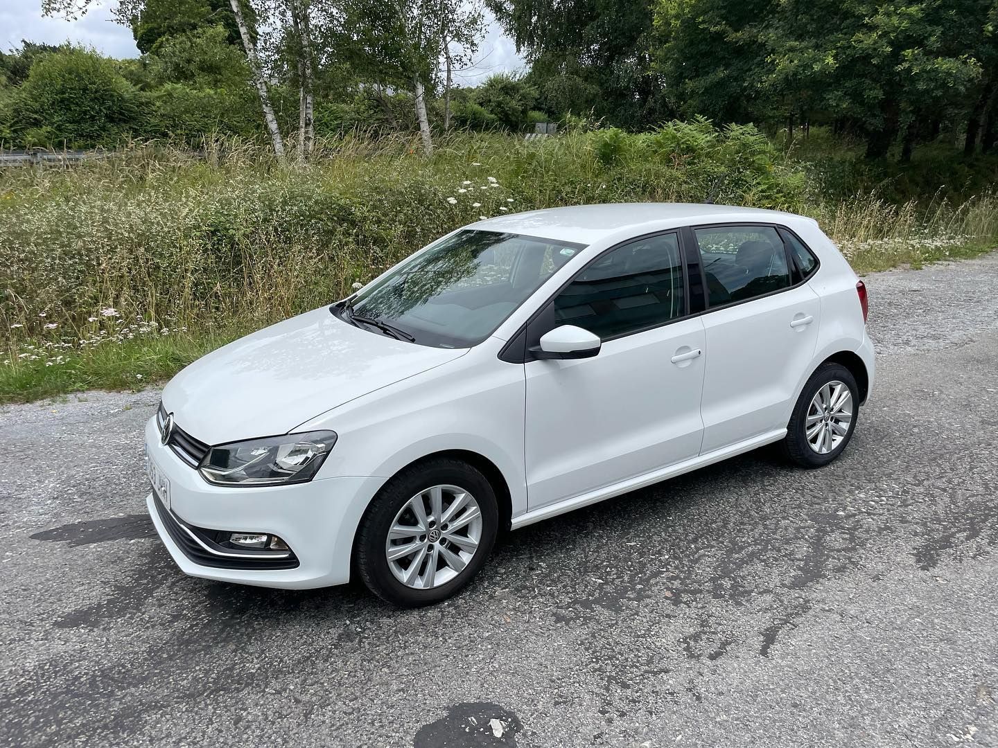 Un Volkswagen Polo blanco está estacionado al costado de una carretera.