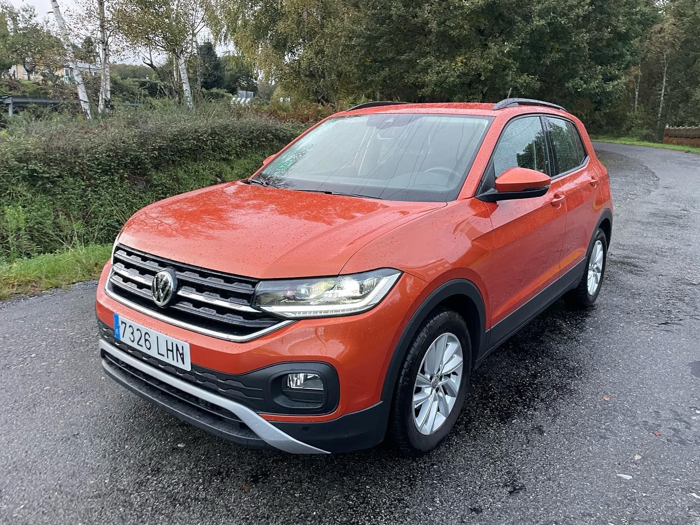 Un Volkswagen T-Cross rojo está estacionado al costado de una carretera.
