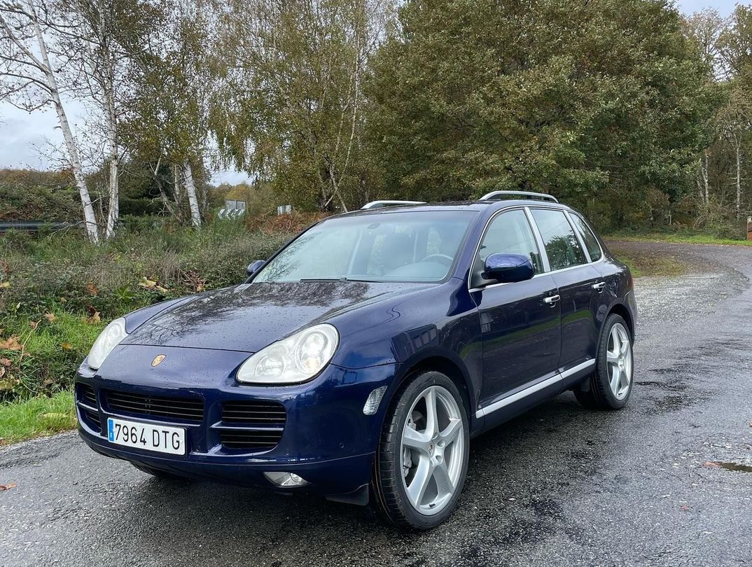 Un Porsche Cayenne azul está estacionado al costado de la carretera.