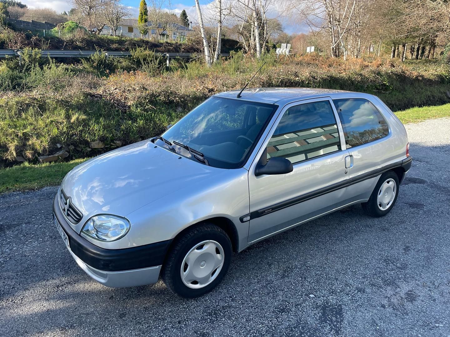 Un coche plateado está aparcado al costado de la carretera.