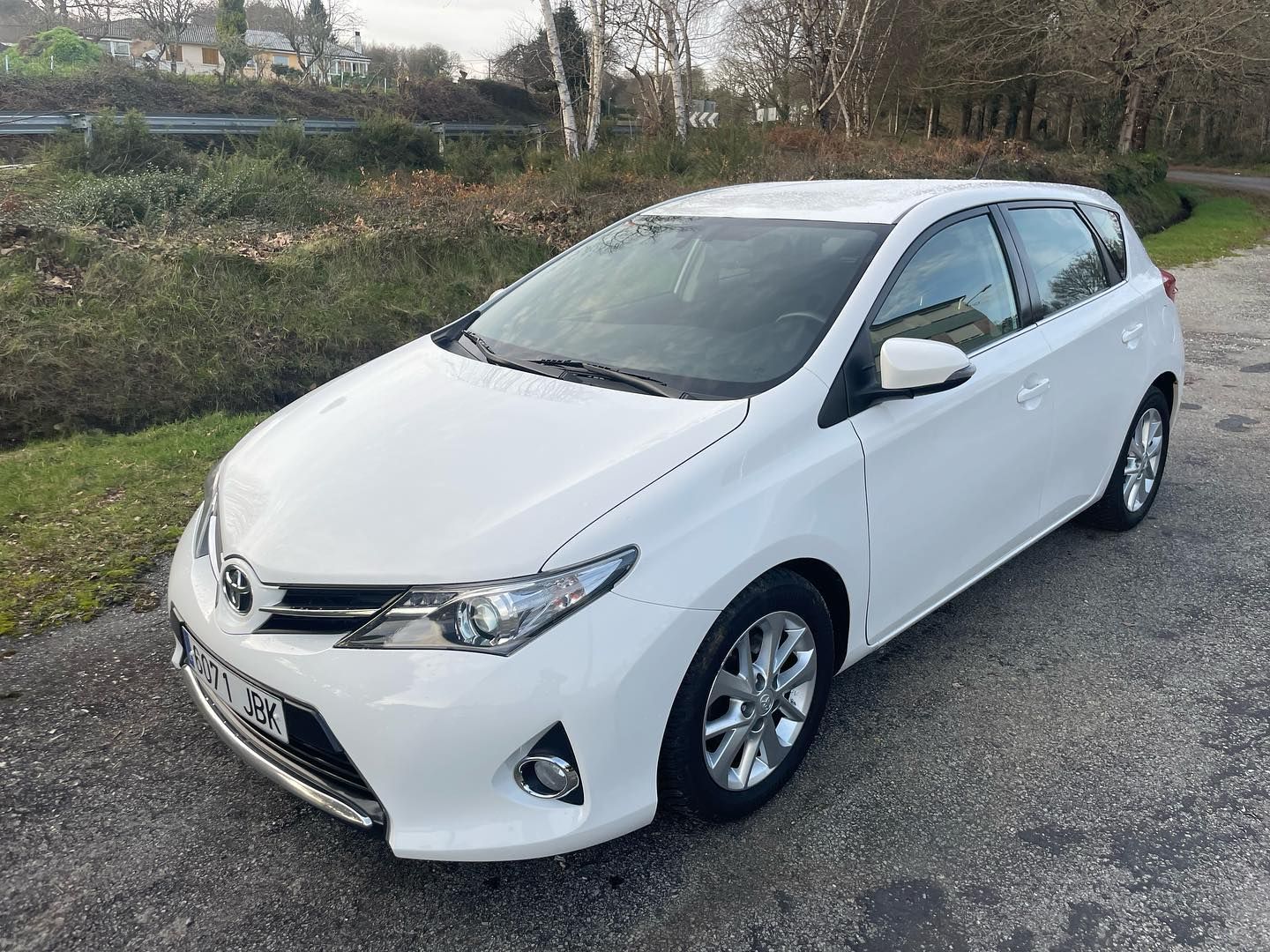 Un Toyota Auris blanco está estacionado al costado de la carretera.