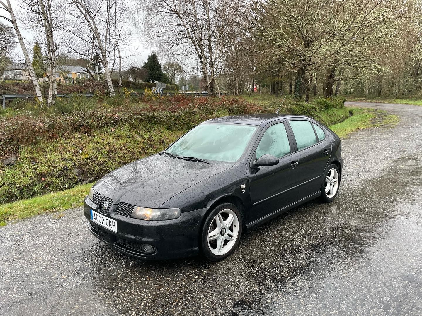 Un coche negro está estacionado al costado de una carretera.