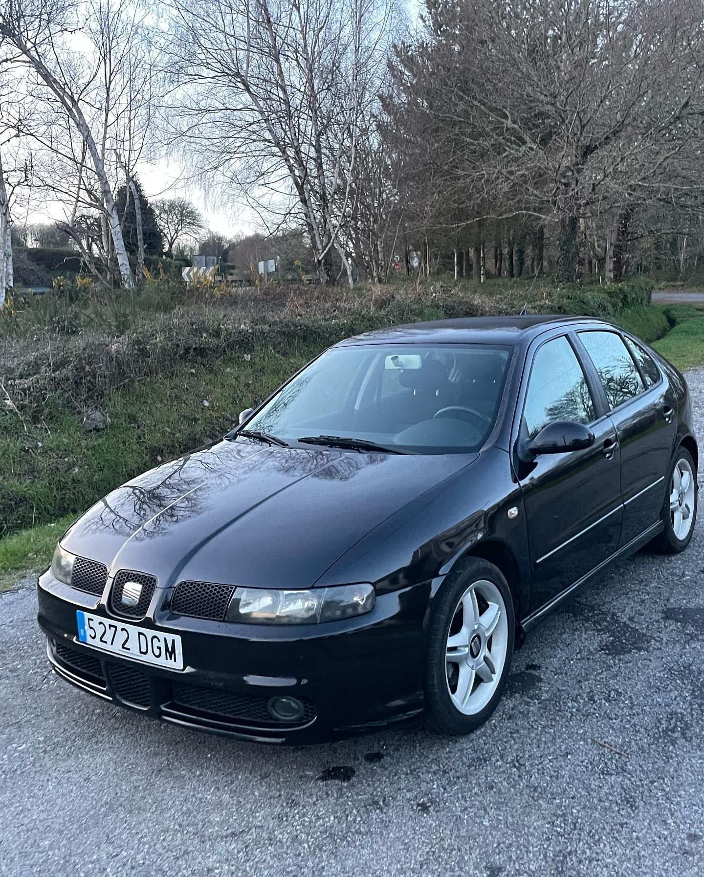 Un coche negro está estacionado al costado de la carretera.