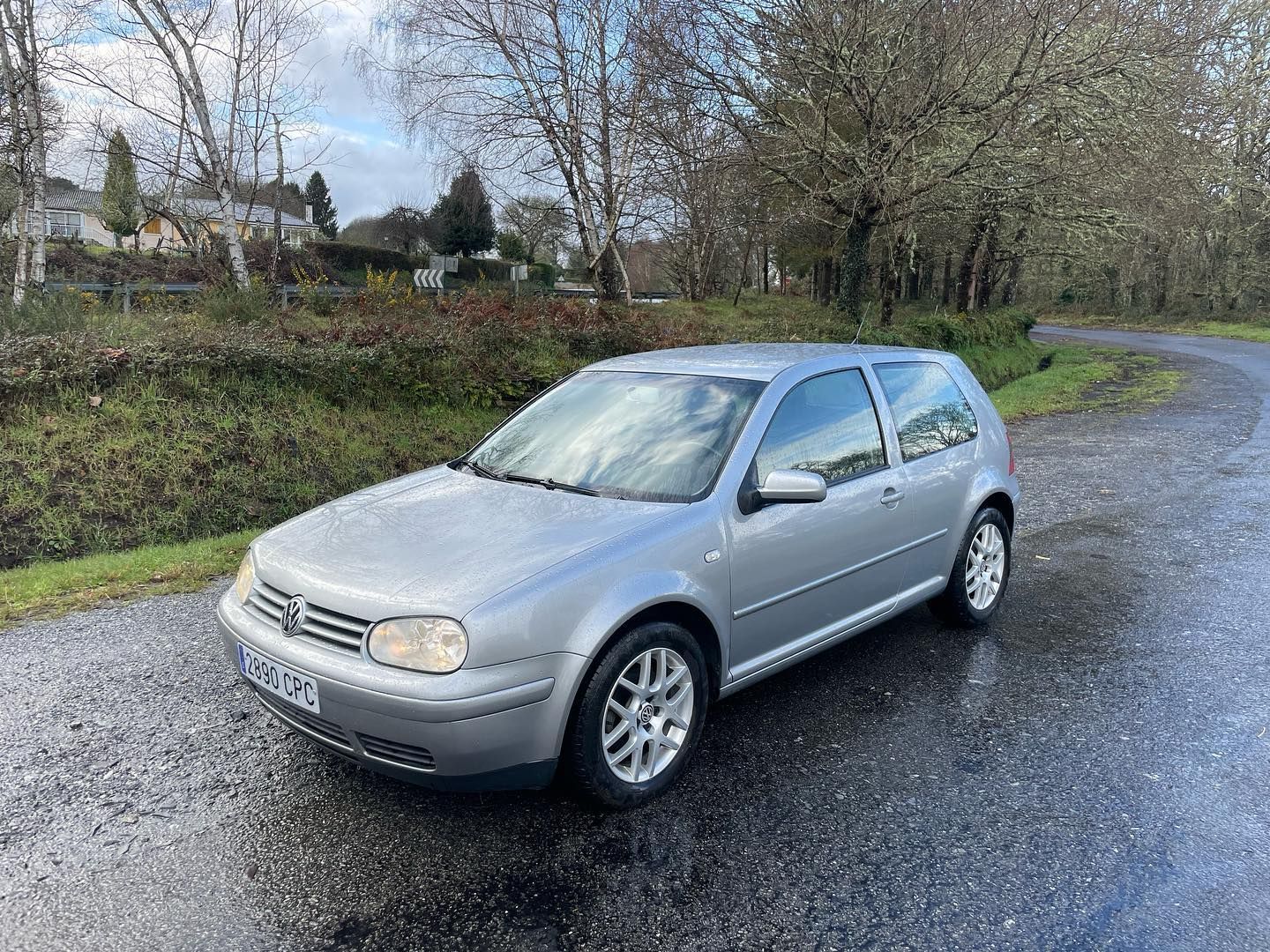 Un Volkswagen Golf plateado está estacionado al costado de una carretera.