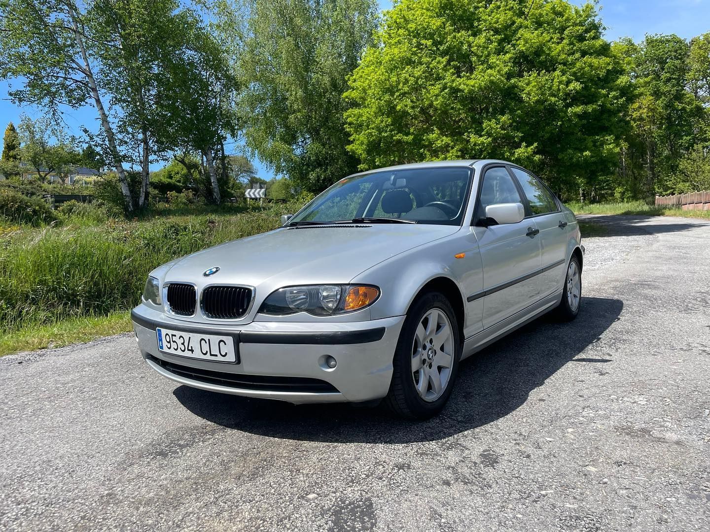 Un BMW plateado está estacionado al costado de la carretera.