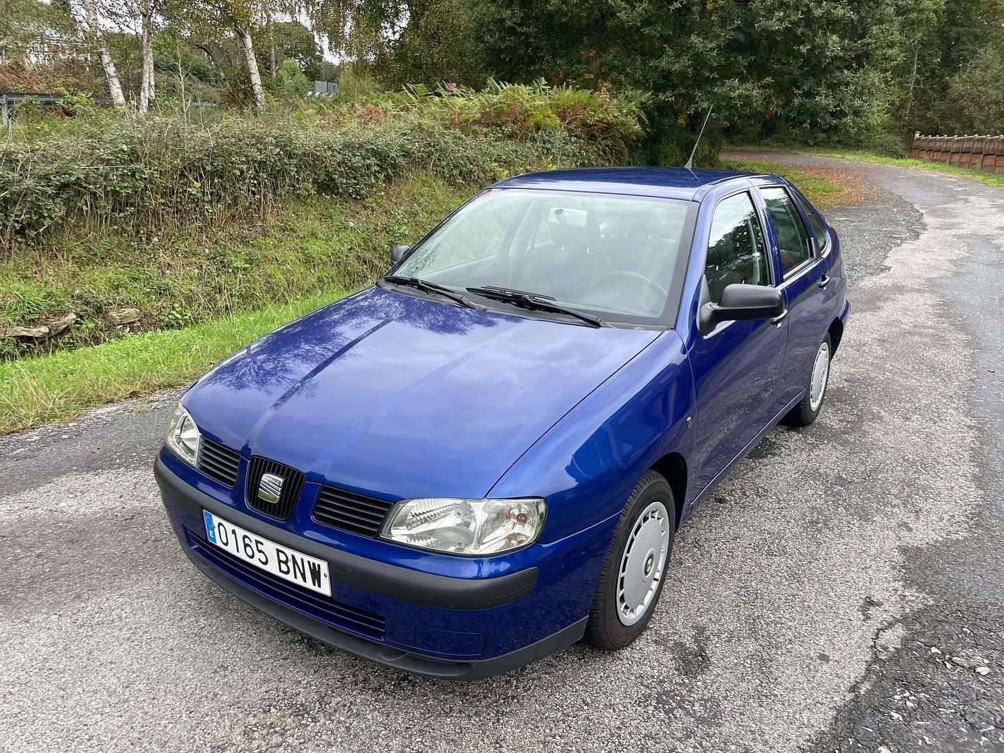 Un coche azul está estacionado al costado de una carretera.