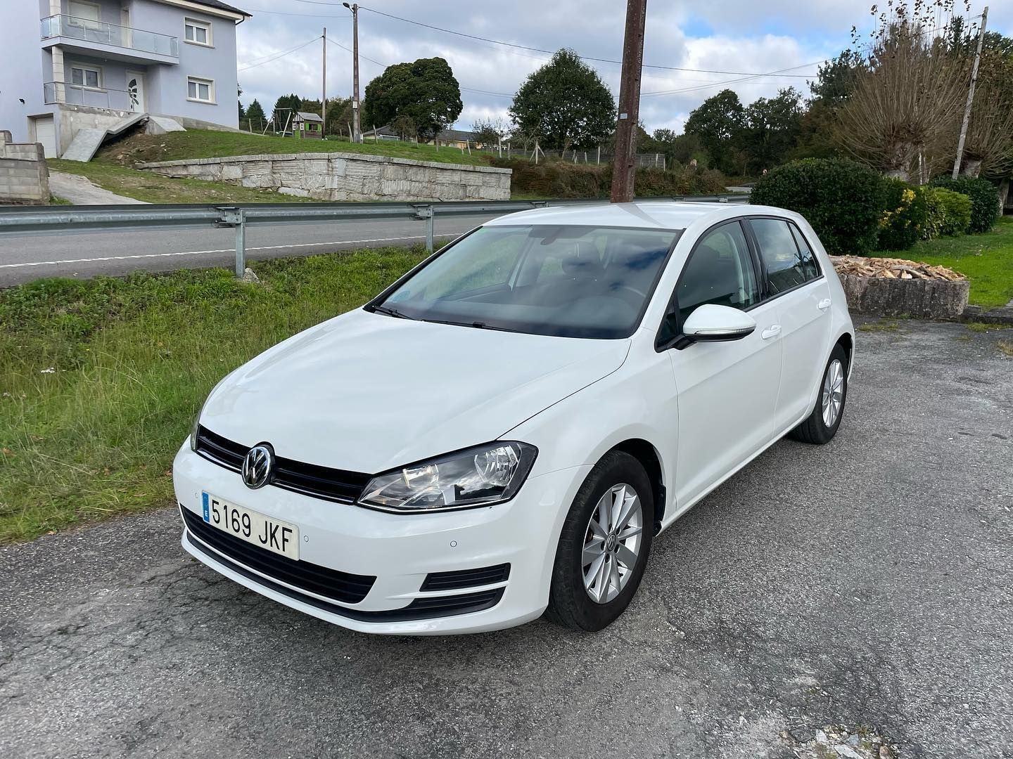 Un Volkswagen Golf blanco está estacionado al costado de la carretera.