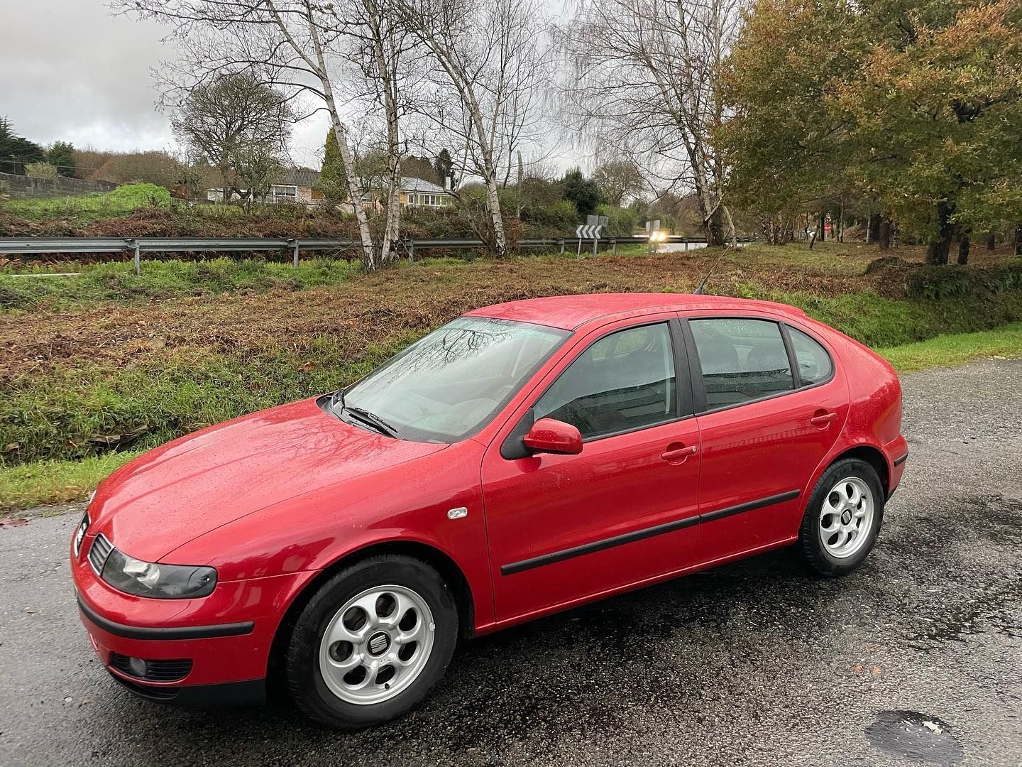Un coche rojo está estacionado al costado de la carretera.