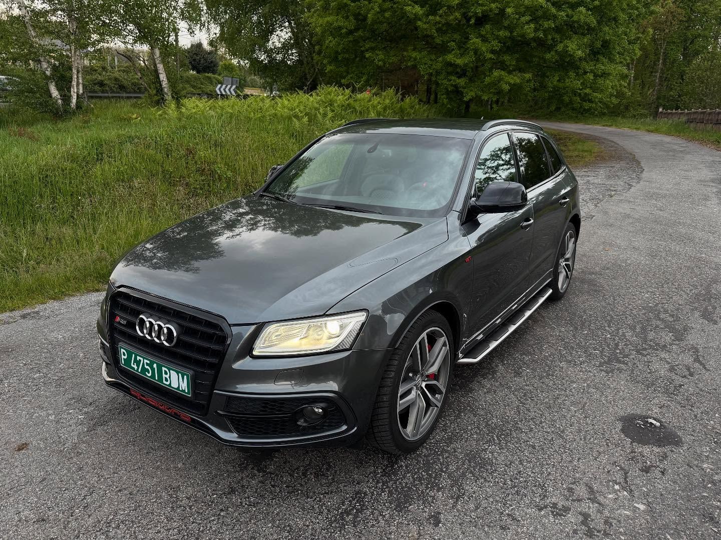 Un Audi Q5 negro está estacionado al costado de una carretera.