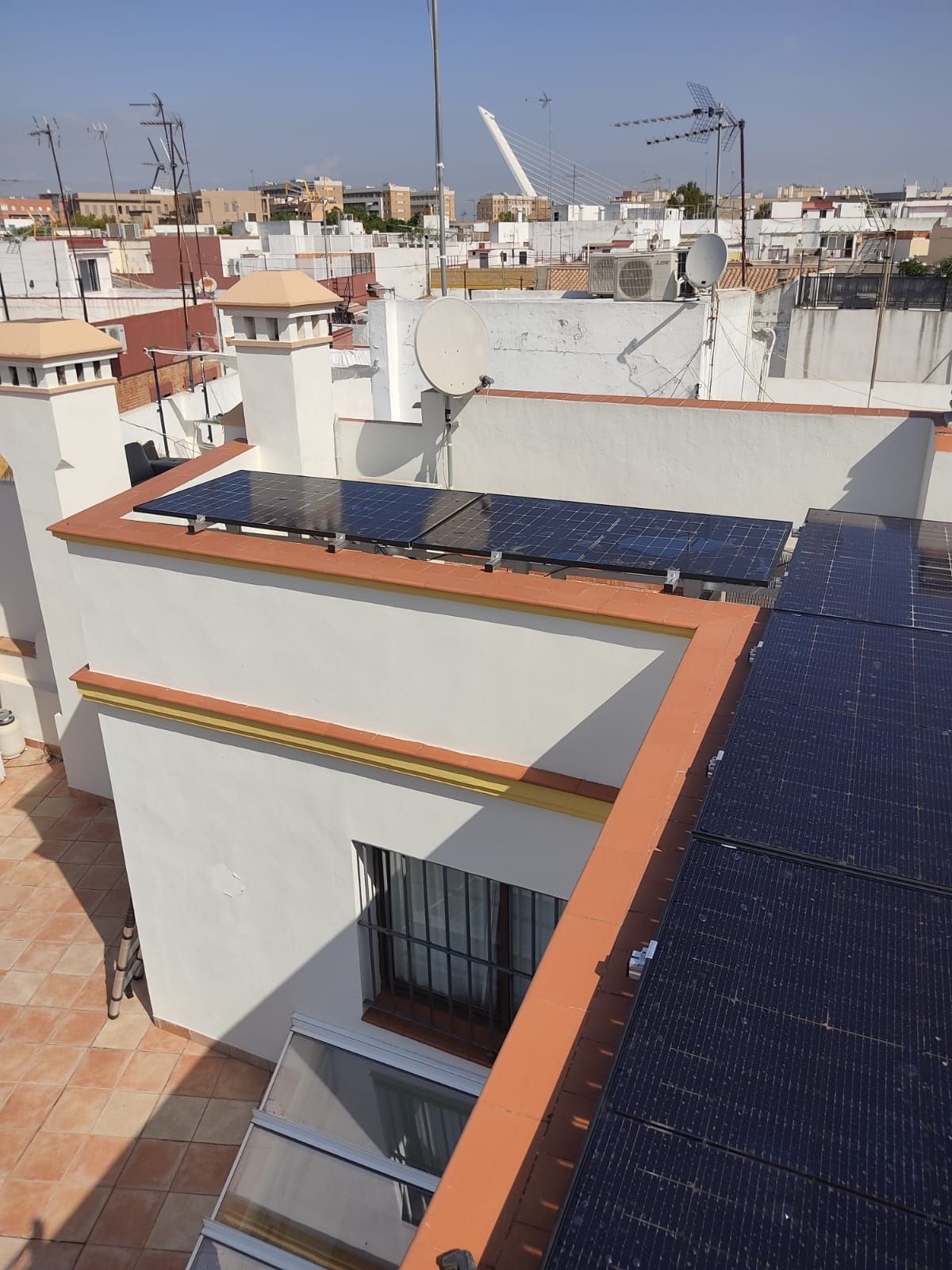 Una mano rellena una lista de verificación para la instalación de paneles solares junto a dos tabletas sobre un escritorio.