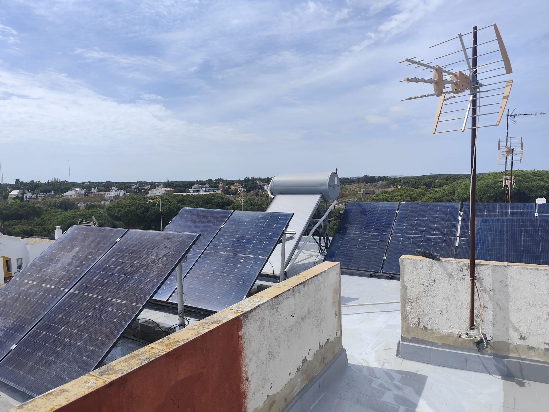 Manos enguantadas instalando paneles solares en un soporte en el tejado bajo un cielo despejado