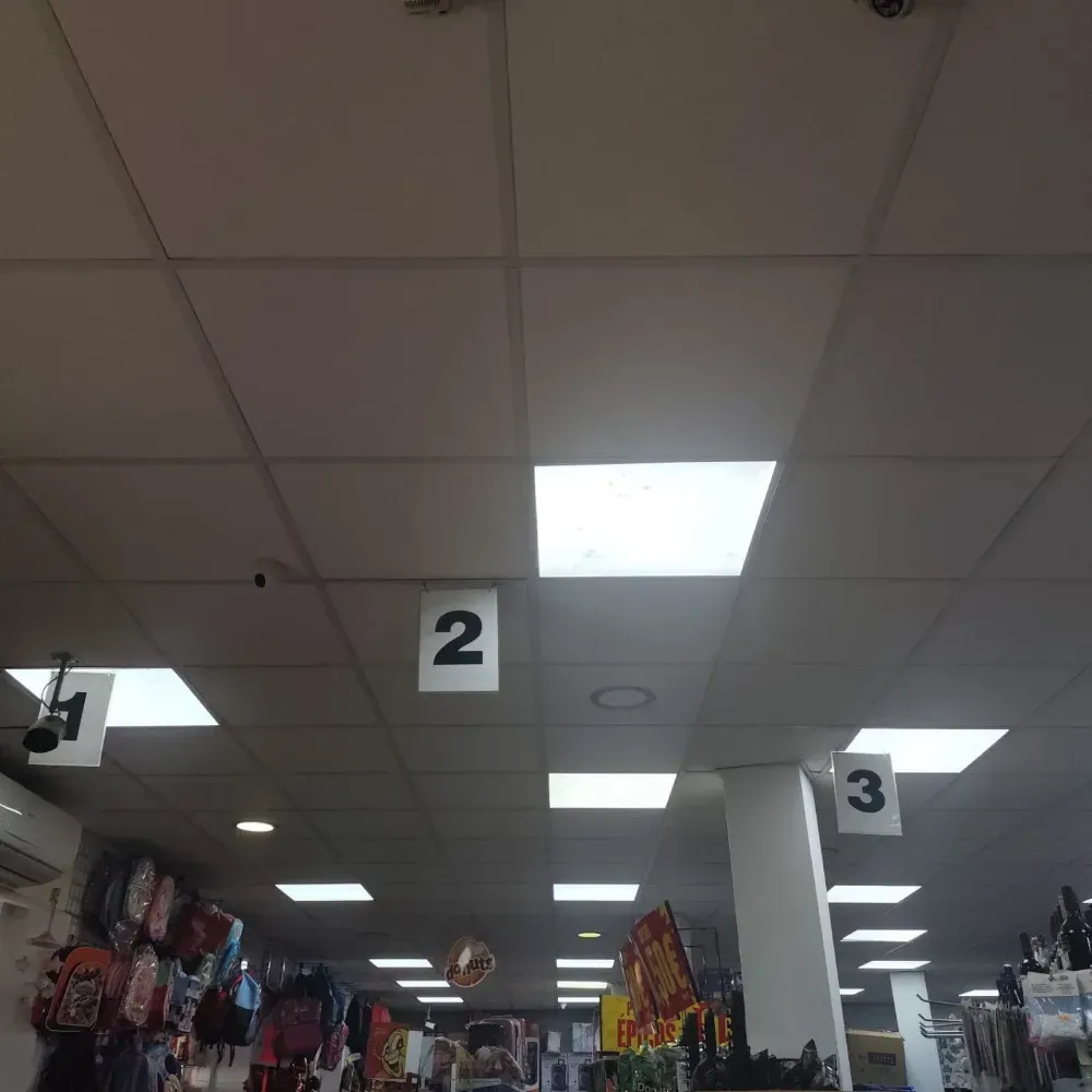 Pasillo de supermercado con letreros colgantes numerados del 1 al 3 bajo luces fluorescentes de techo.
