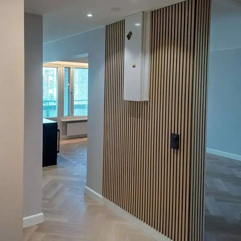 Moderni asunnon eteinen, jossa on sälepohjainen koristeseinä, valkoiset kaapit ja kalanruotokuvioinen lattia