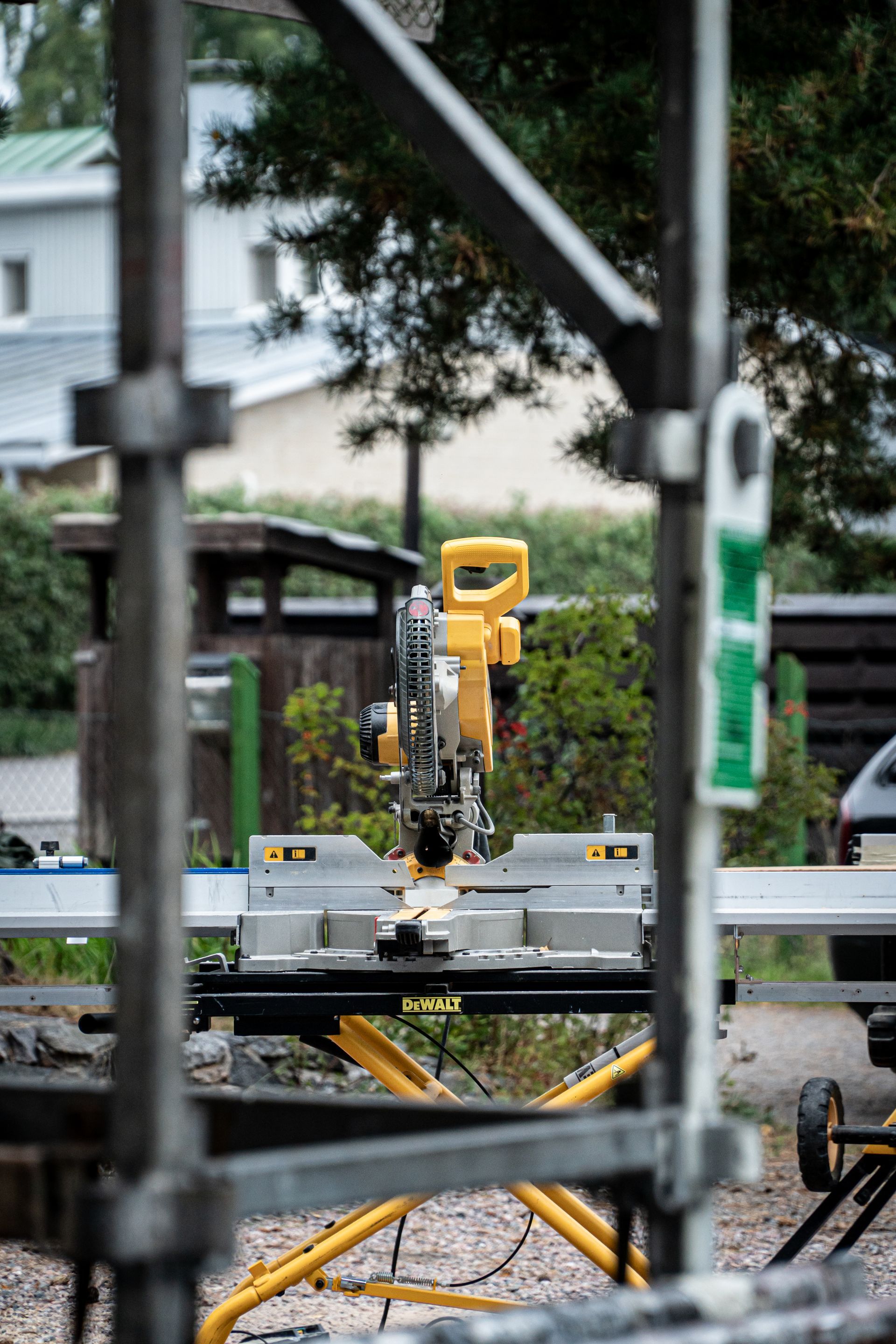 Katettu punainen rakennuksen sisäänkäynti betoniportailla, lasiovilla ja tiilistä tehdyllä kävelytiellä maisemoidulla ulkoalueella