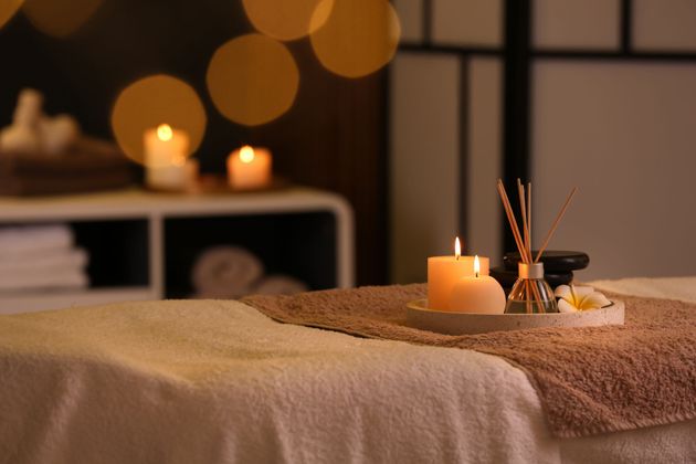 Scena di spa con asciugamani arrotolati, candele e diffusore di aromaterapia.
