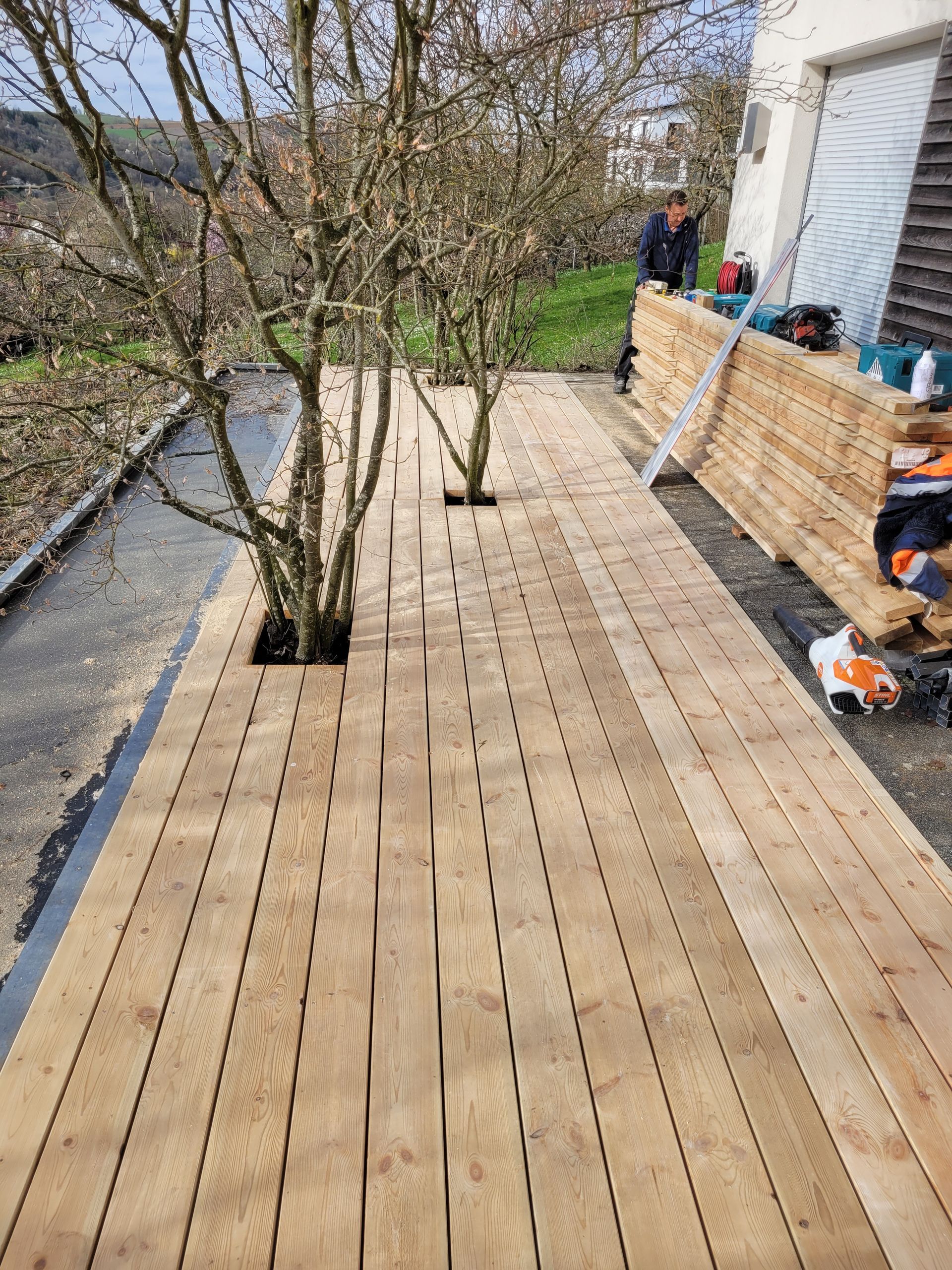 Person, die im Freien mit einer Bohrmaschine Holzplanken befestigt.