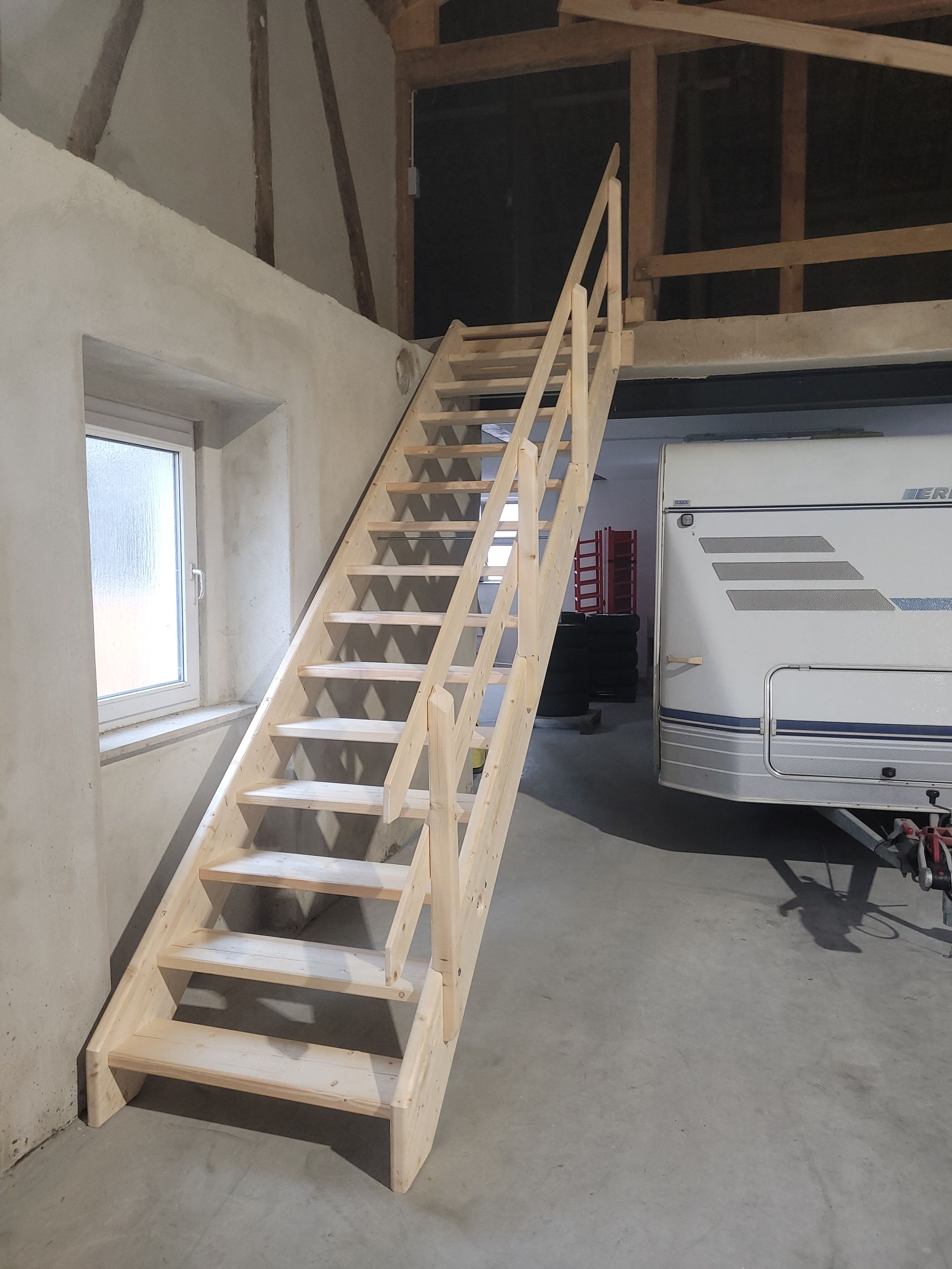 Ein Bauarbeiter steht auf einem hölzernen Dachstuhl und zeigt nach oben. Blauer Himmel ist zu sehen.