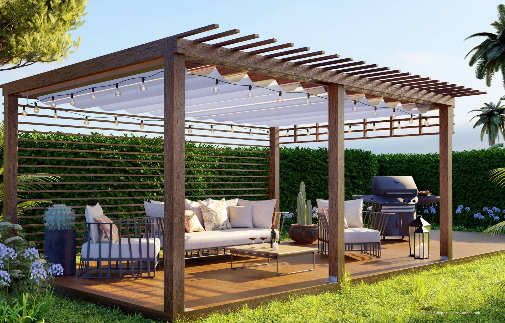 Terrasse mit Pergola, Sitzgelegenheiten und Grill. Braunes Holz, weiße Stoffe, grünes Laub in sonniger Lage.