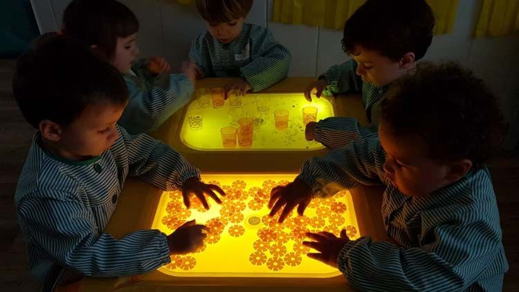 Un grupo de niños está jugando con una mesa de luz.