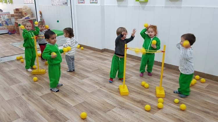 Un grupo de niños está jugando con pelotas amarillas en una habitación.