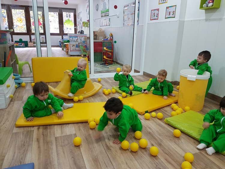 Un grupo de niños está jugando con pelotas amarillas en una habitación.