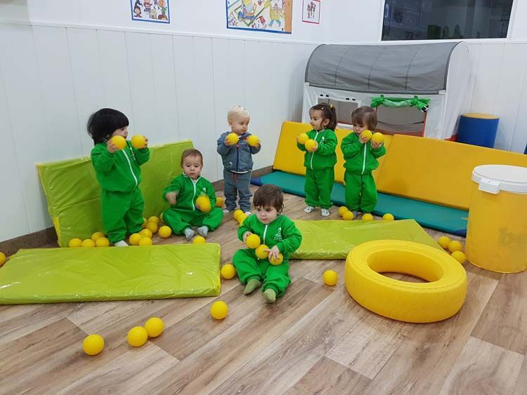 Un grupo de niños está jugando con pelotas amarillas en una habitación.