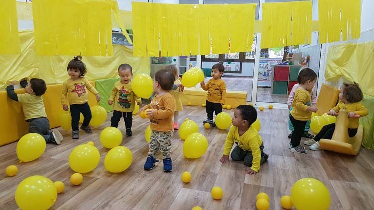 Un grupo de niños está jugando con globos amarillos en una habitación.