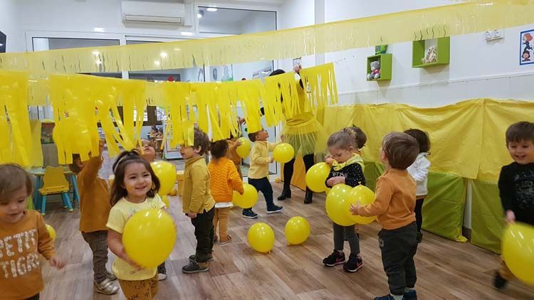 Un grupo de niños está jugando con globos amarillos en una habitación.