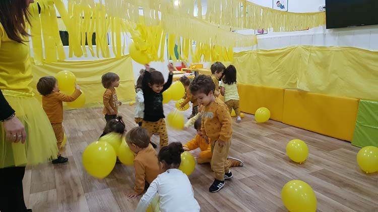 Un grupo de niños está jugando con globos amarillos en una habitación.