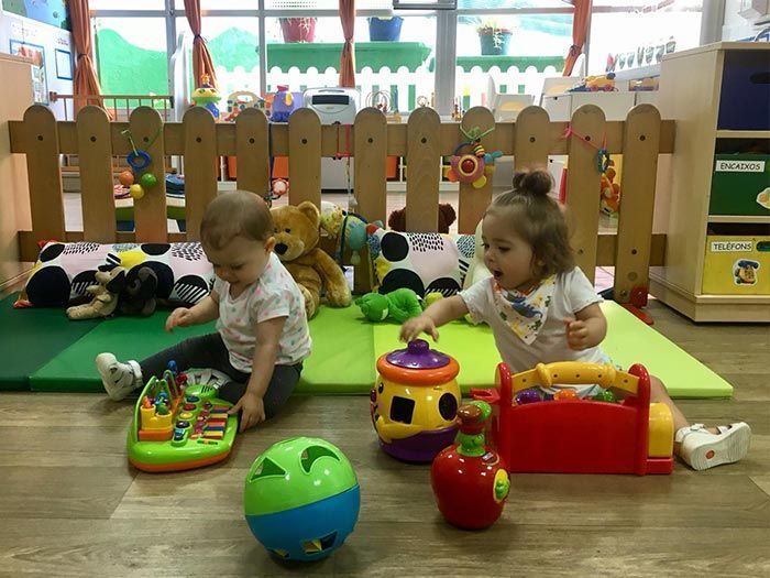 Dos niñas están sentadas en el suelo jugando con juguetes.