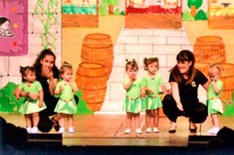 Un grupo de niñas con vestidos verdes están de pie en un escenario.