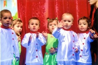 Un grupo de niños está parado frente a una cortina roja.