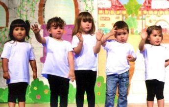 Un grupo de niños que visten camisas blancas y pantalones negros están parados uno al lado del otro.