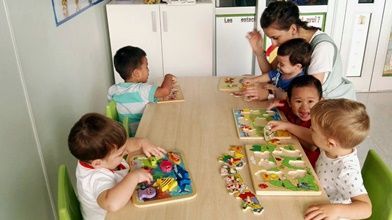 Un grupo de niños está sentado en una mesa jugando con rompecabezas.