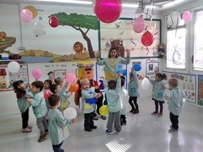 Un grupo de niños sostiene globos en una habitación.