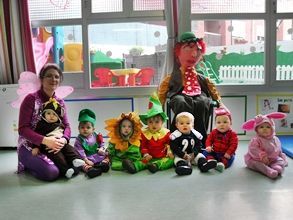 Un grupo de bebés vestidos con disfraces están sentados en el suelo.