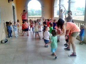 Un grupo de niños está bailando en una habitación con una mujer parada junto a ellos.