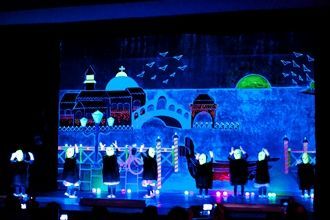 Un grupo de personas está bailando en un escenario frente a una pantalla grande.