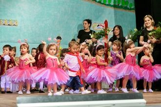 Un grupo de niños con tutús rosas bailan en un escenario.