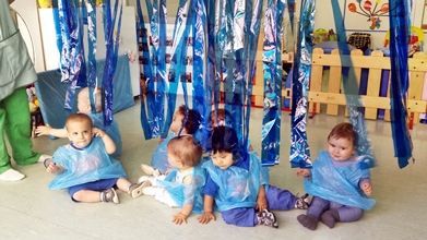 Un grupo de bebés están sentados en el suelo bajo cintas azules.